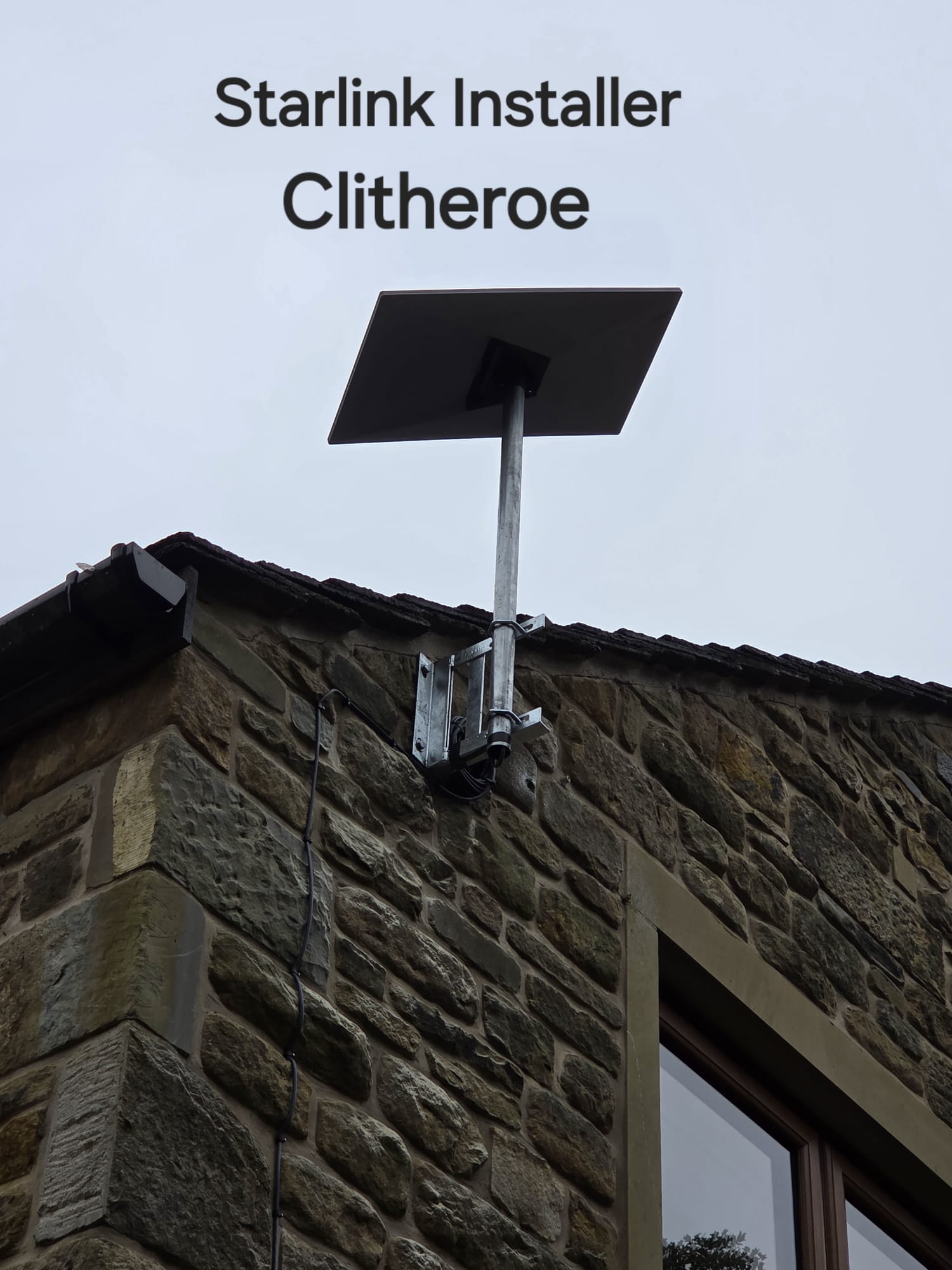 Starlink dish on a metal pole with twin brackets fixed to a stone wall in Clitheroe